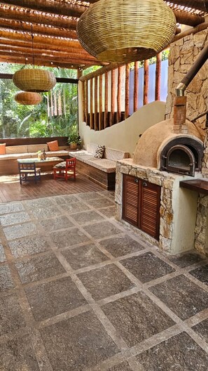 An outdoor seating area with stone flooring, a stone fireplace, and hanging woven light fixtures. -  Casa Cacau Buzios (Búzios)