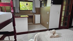 A room with a bunk bed, a small kitchenette, a window with curtains, and a bed with rolled towels. -  Casa Cacau Buzios (Búzios)