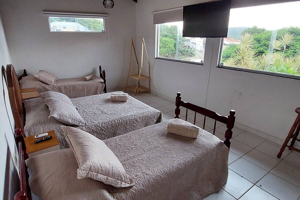 Una habitación con dos camas, una escalera de madera, un televisor y una ventana con vistas al verdor.