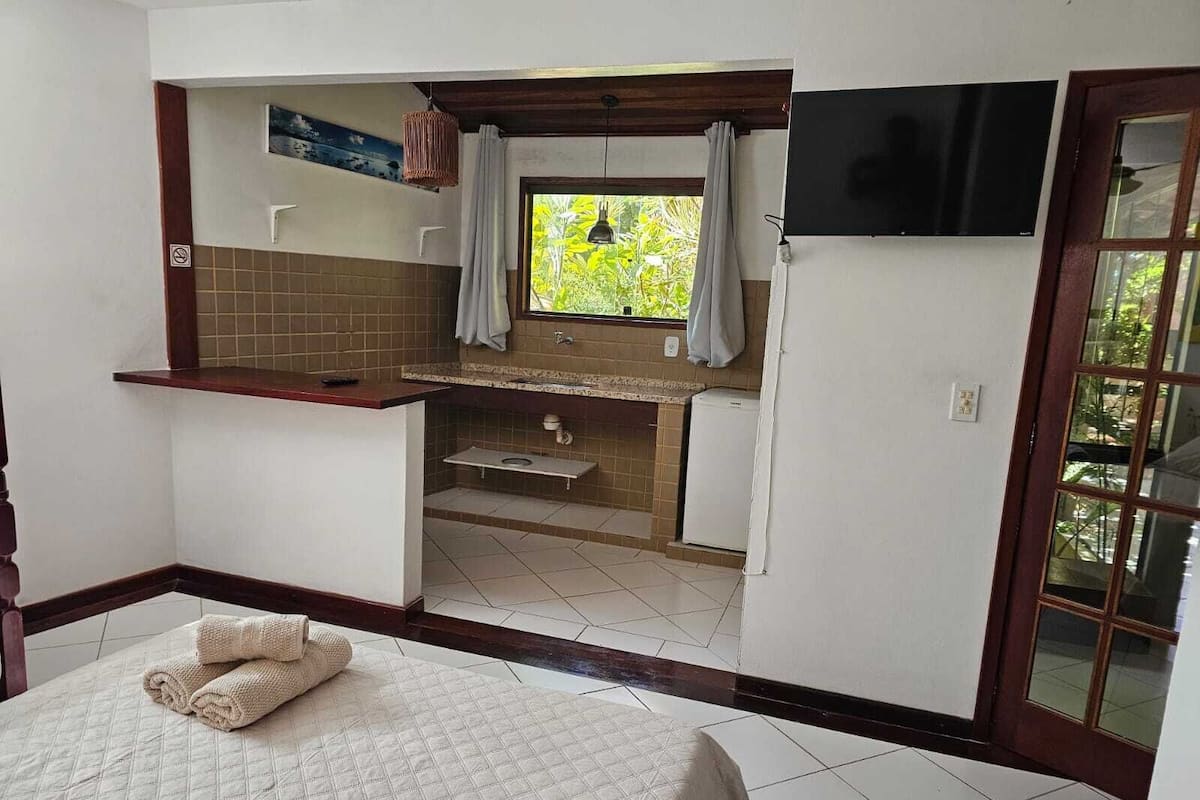 Una habitación compacta con cama, un pequeño kitchenette y una ventana con cortinas.