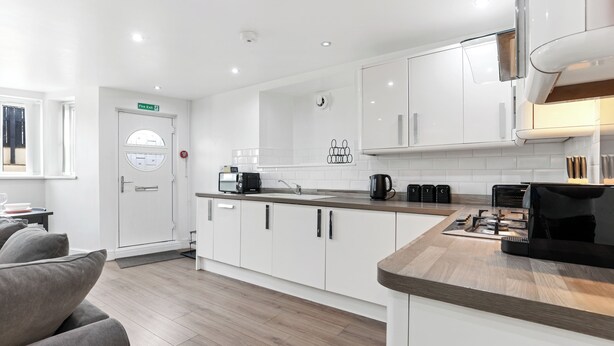 A modern kitchen with white cabinets, a wooden countertop, and a built-in stove. - The Hamlet - North East Escapes (North Shields)