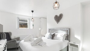 A modern hotel room with a large bed, a desk, a chair, and a small bedside table. - The Hamlet - North East Escapes (North Shields)