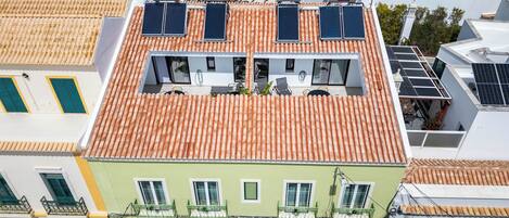 A building with a flat roof, solar panels, and a balcony with a railing.
