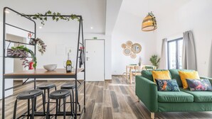 Una cucina moderna con zona bar, un divano verde con cuscini colorati e una lampada a sospensione.