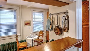 Een keuken met een houten tafel, twee stoelen, een radiator en een messenhouder aan de muur.