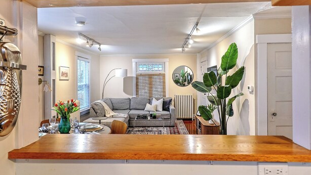 Een moderne woonkamer met een grijze bank, een salontafel en een eethoek met een houten tafel en stoelen.