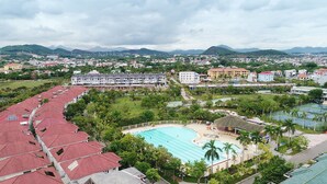 A hotel with a swimming pool, surrounded by greenery and a view of distant mountains. - Teky House 2 (Hue)
