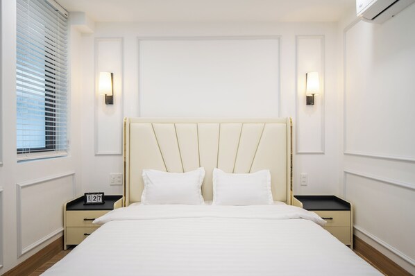 Un dormitorio ordenado con una cama, dos mesitas de noche y lámparas de pared.