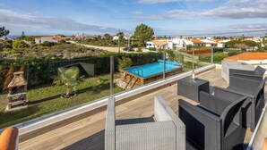 A rooftop terrace with a swimming pool, outdoor furniture, and a view of a residential area.