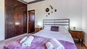 A bedroom with a large bed, wooden wardrobe, and decorative wall art.