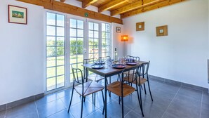 A dining area with a wooden ceiling, large windows, and a tiled floor.