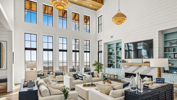 A spacious living room with multiple seating areas, a large TV, and a bookshelf.