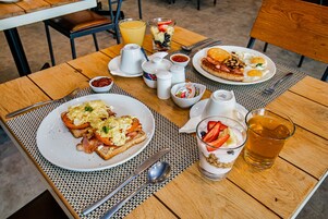 A breakfast table with plates of eggs, toast, and fruit, a pitcher, salt and pepper shakers, and a glass of juice.