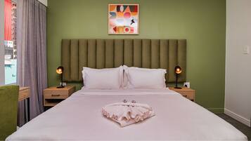 Quarto de hotel com cama grande, duas mesas de cabeceira, cabeceira e um quadro na parede.