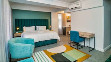 A hotel room with a bed, a desk, a chair, a bathroom, and an air conditioning unit.