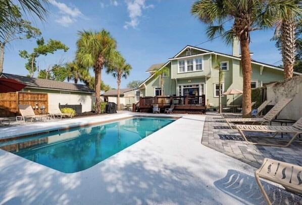 A swimming pool with lounge chairs, a wooden deck, and a house with a porch. - Charming 3-bedroom loft unit  with WiFi and AC in the Heart of San Marco (Jacksonville)