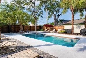 A rectangular swimming pool with lounge chairs and a wooden fence in the background. - Charming 3-bedroom loft unit  with WiFi and AC in the Heart of San Marco (Jacksonville)
