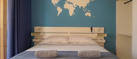 A bed with a world map on the wall, a bedside table, and a curtain.