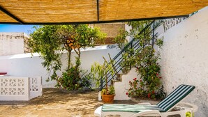 A covered outdoor area with a white wall, a staircase, and a potted plant. There are two white lounge chairs with green stripes. - Casa Los Profesores · Traditional Canarian Charm (La Orotava)