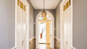 A hallway with white doors, a patterned floor, and a chandelier. - Casa Los Profesores · Traditional Canarian Charm (La Orotava)