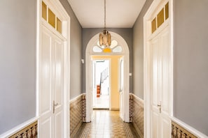 A hallway with white doors, a patterned floor, and a chandelier.