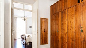 A hallway with a wooden wardrobe, a dining area with a chandelier, and a door leading to another room. - Casa Los Profesores · Traditional Canarian Charm (La Orotava)