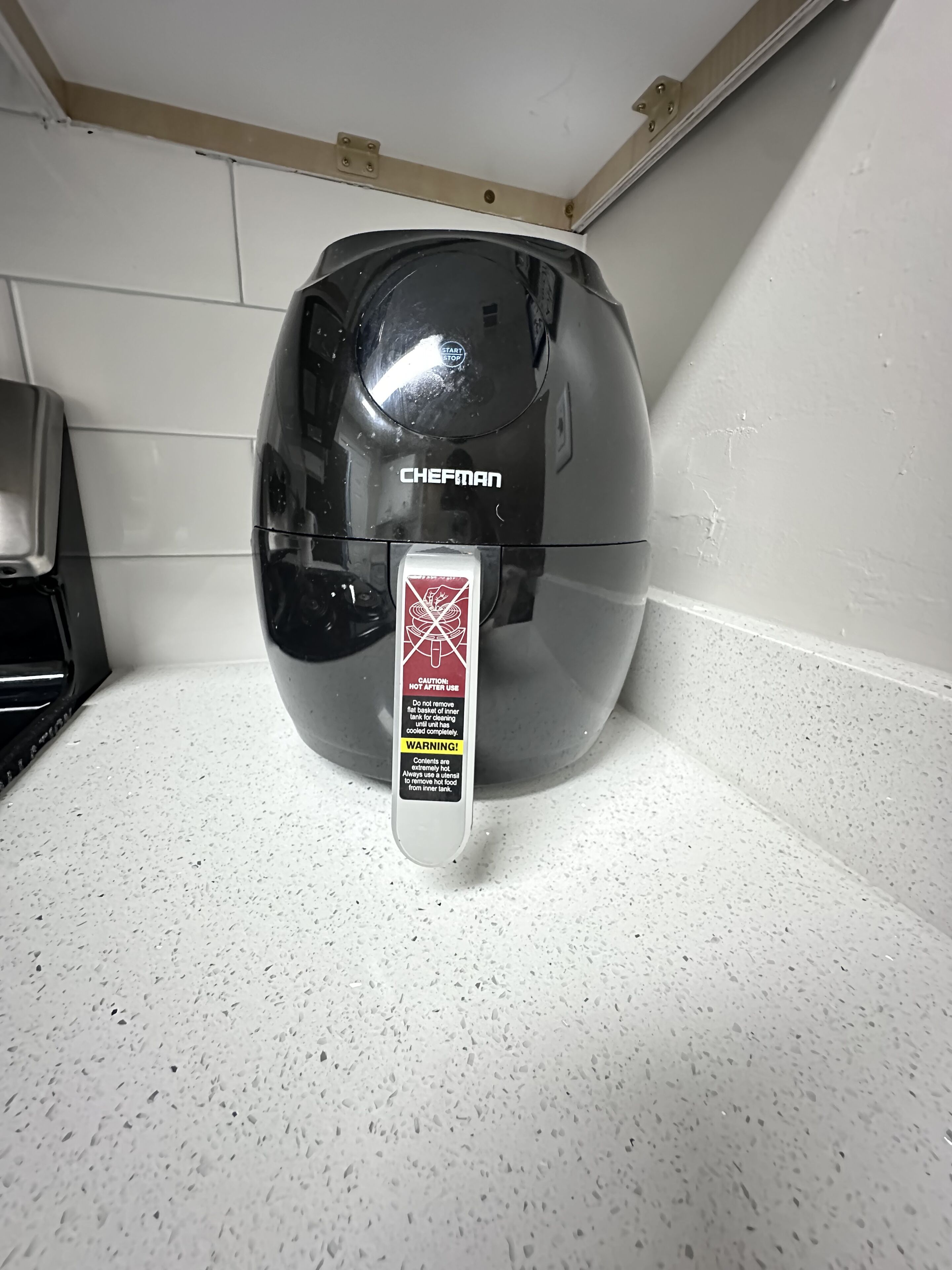 A black water heater with a caution label on the handle.