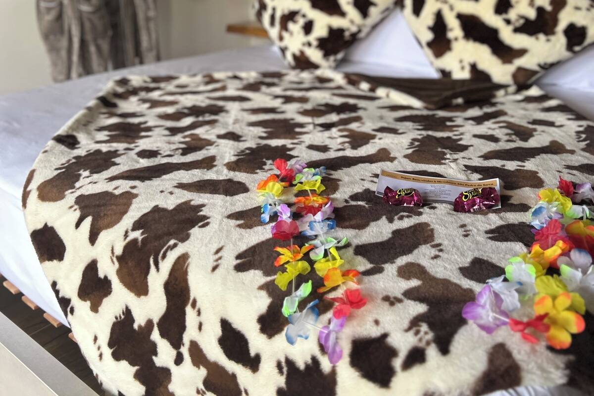 A bed with a cow print blanket, colorful flowers, and a wooden headboard.