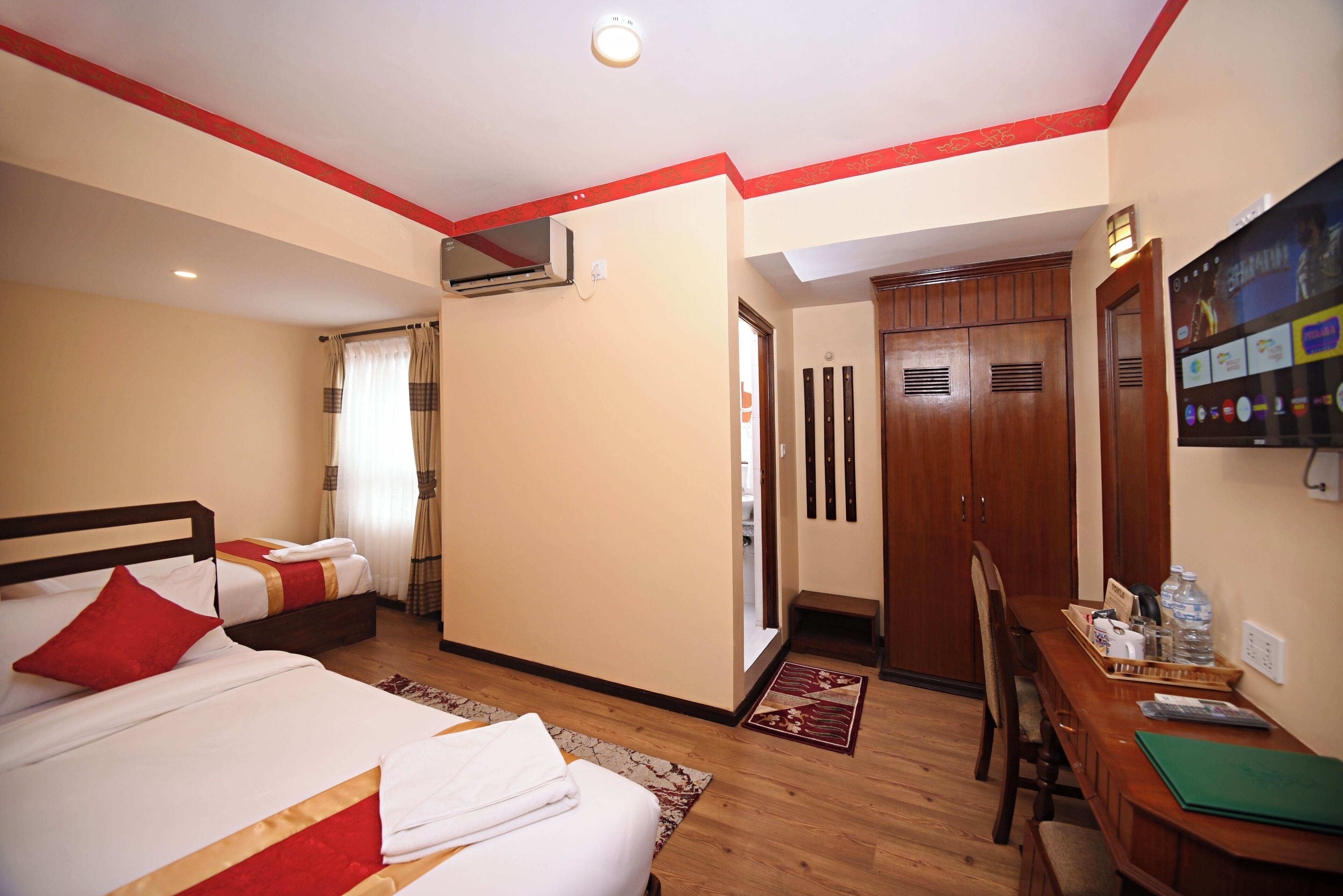 A hotel room with two beds, a desk, and a wardrobe.