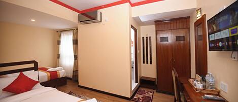 A hotel room with two beds, a desk, and a wardrobe.