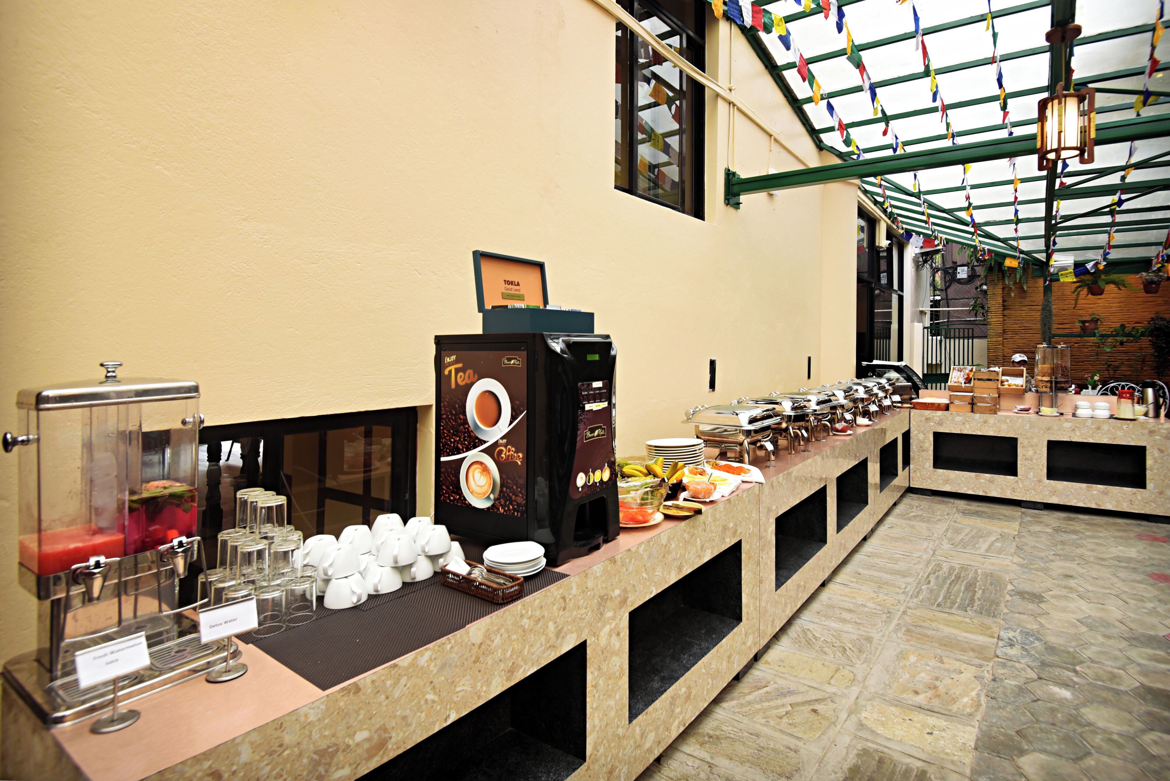A buffet setup with a coffee machine, tea dispenser, and various food items.