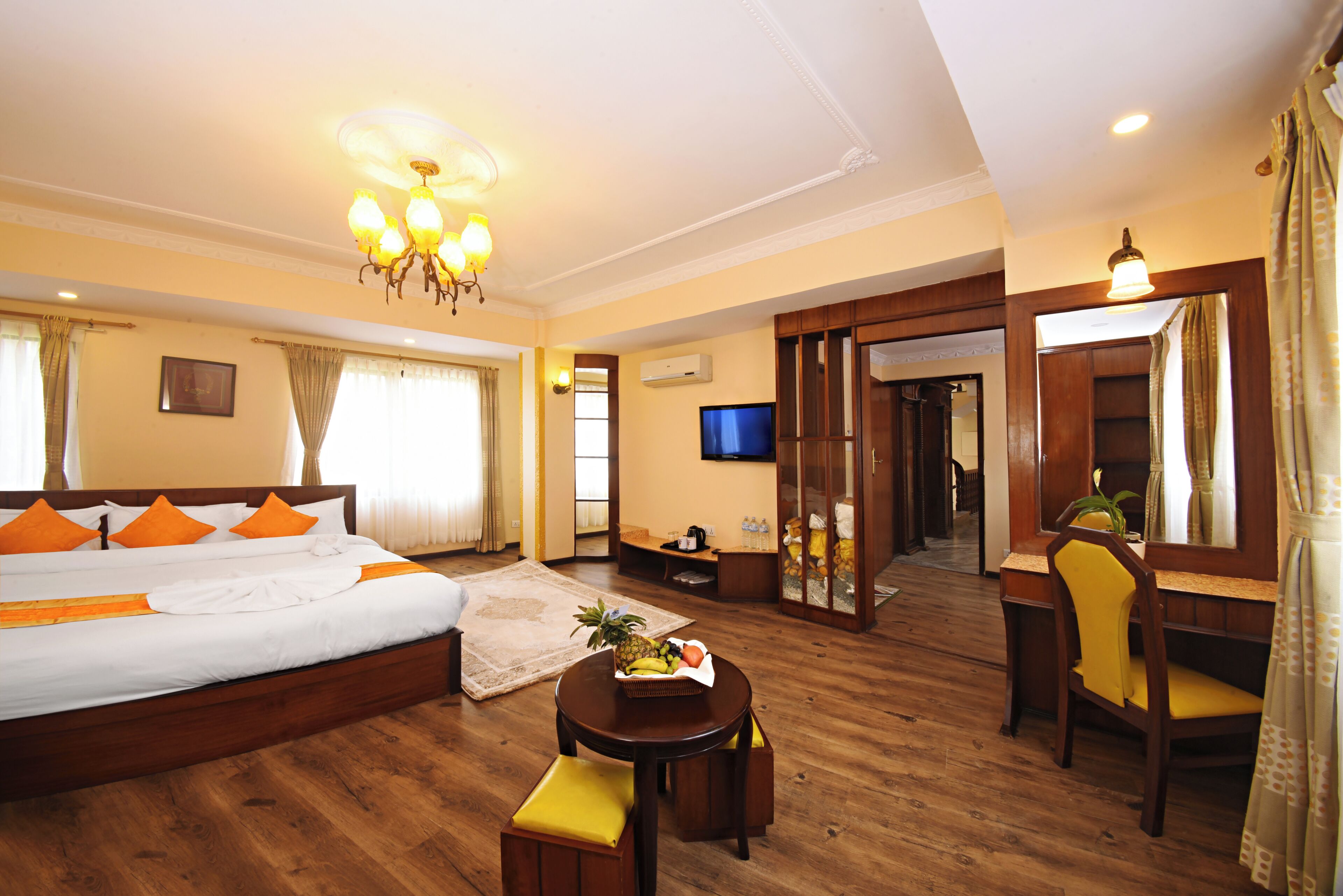 A hotel room with a large bed, a desk, a chair, a television, and a mirror.