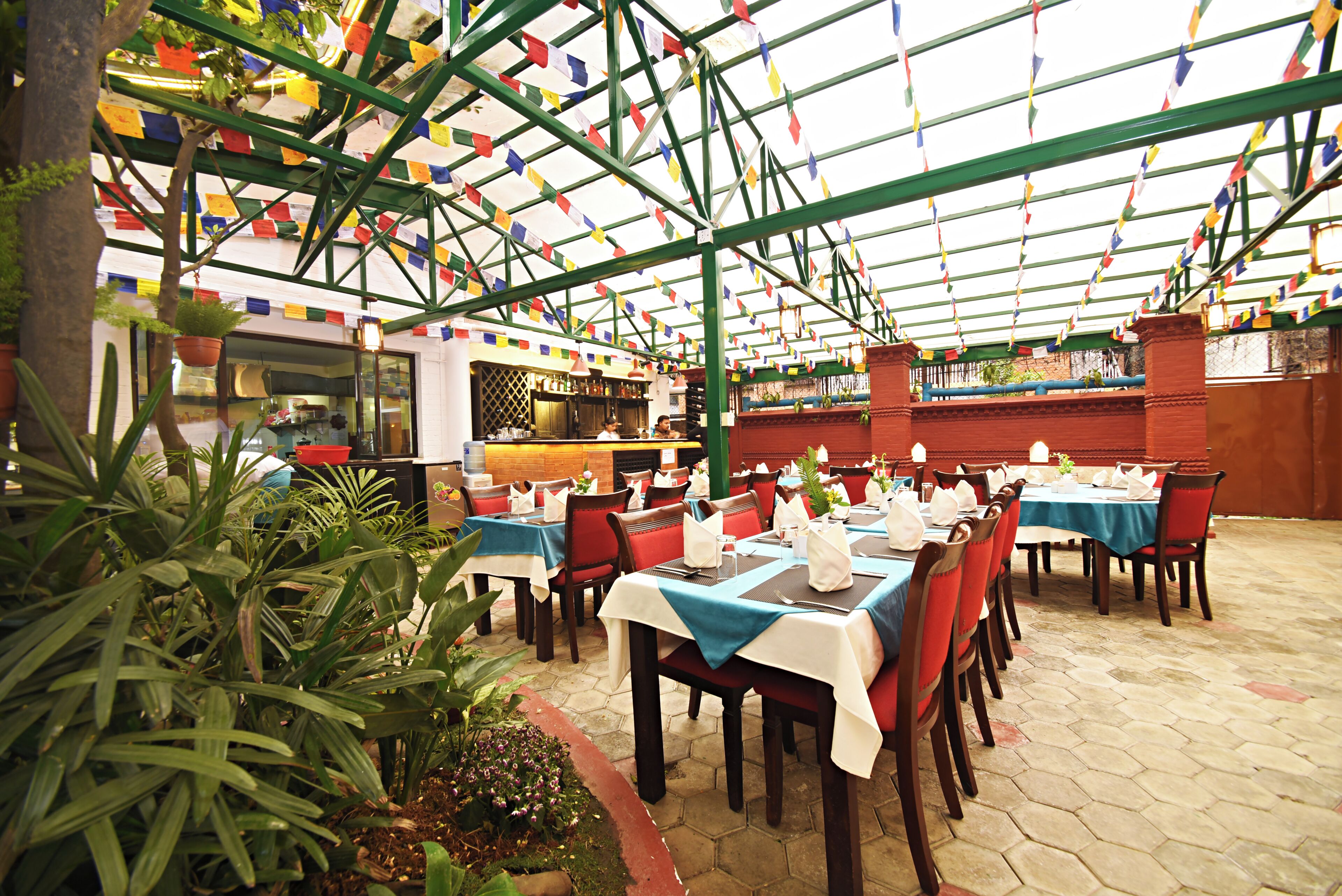 An indoor restaurant with tables covered in white tablecloths and red chairs.