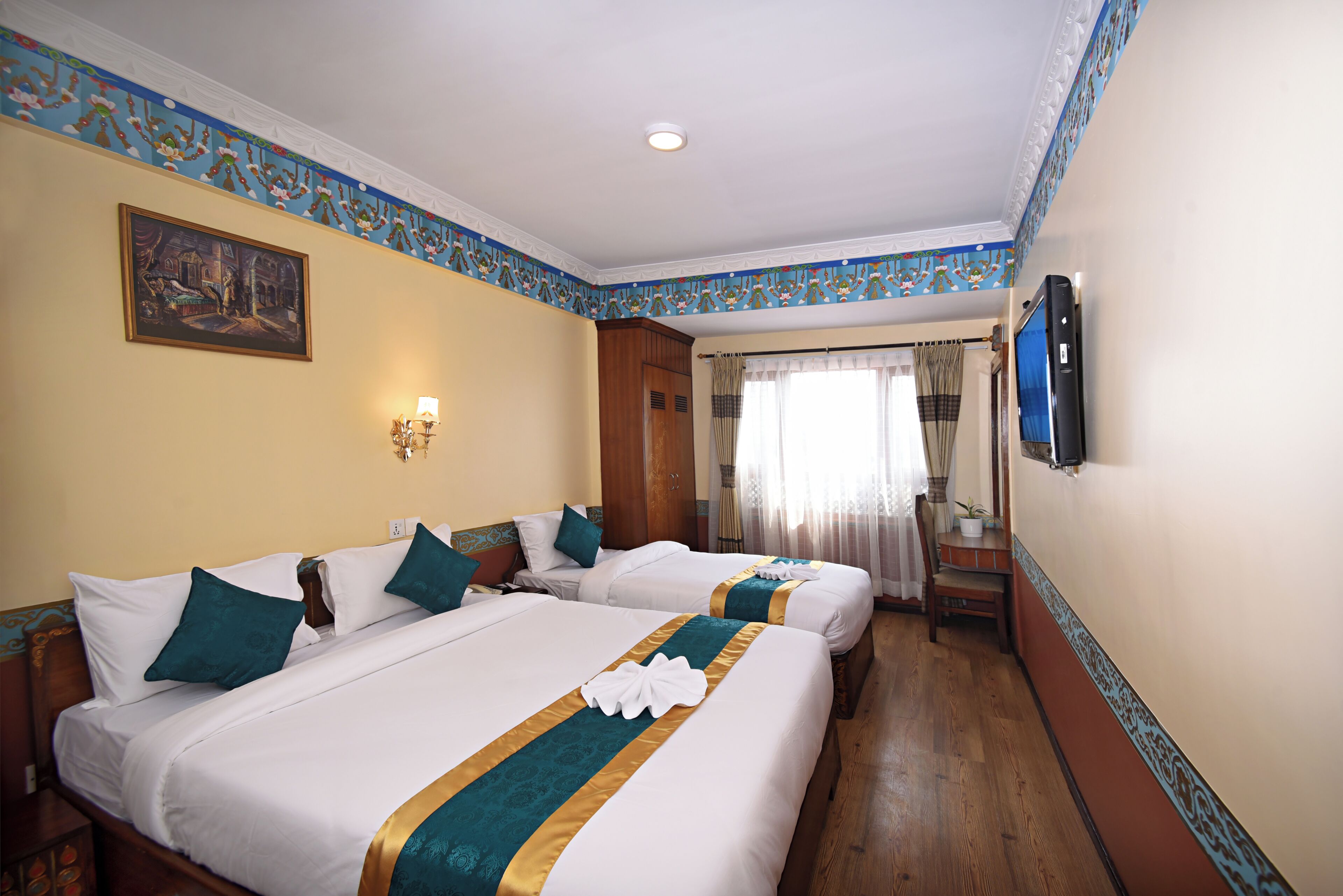 Habitación de hotel con dos camas, un cuadro en la pared, un televisor y una ventana con cortinas.