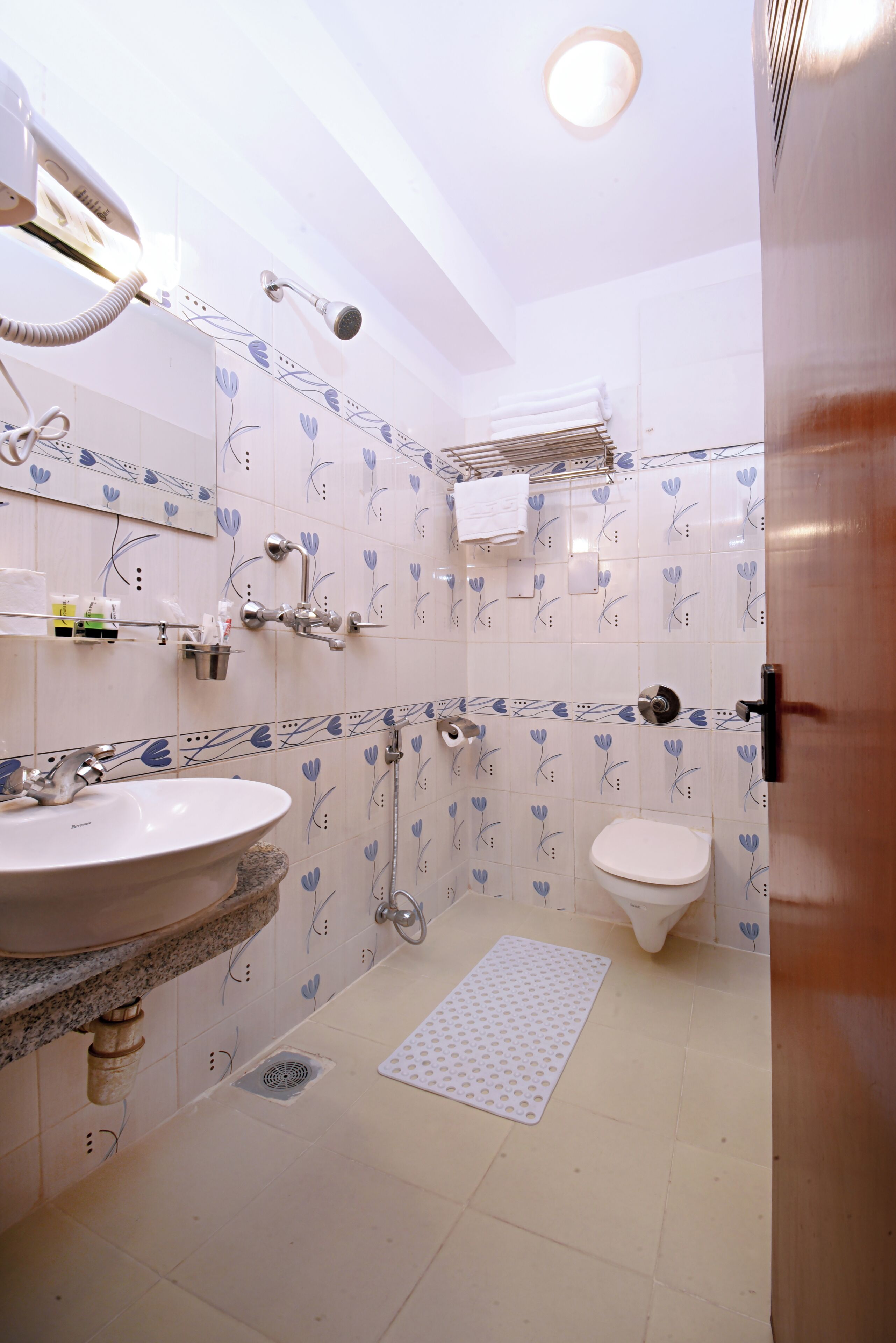 Un baño con lavamanos, inodoro y ducha. Hay toallas y artículos de aseo en la pared.