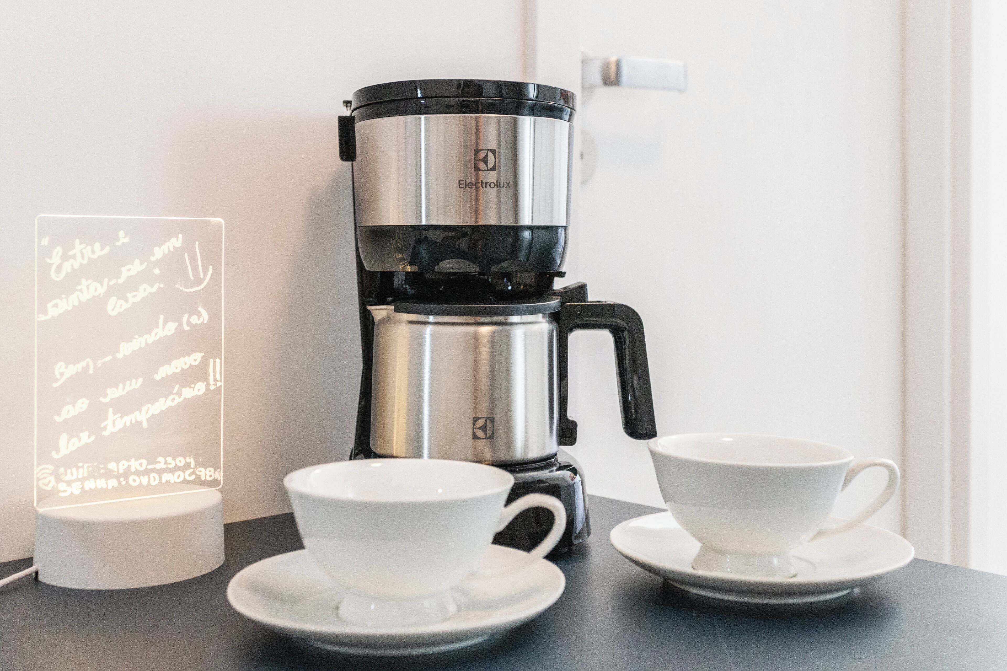Eine Kaffeemaschine mit zwei weißen Tassen auf einem Tisch.