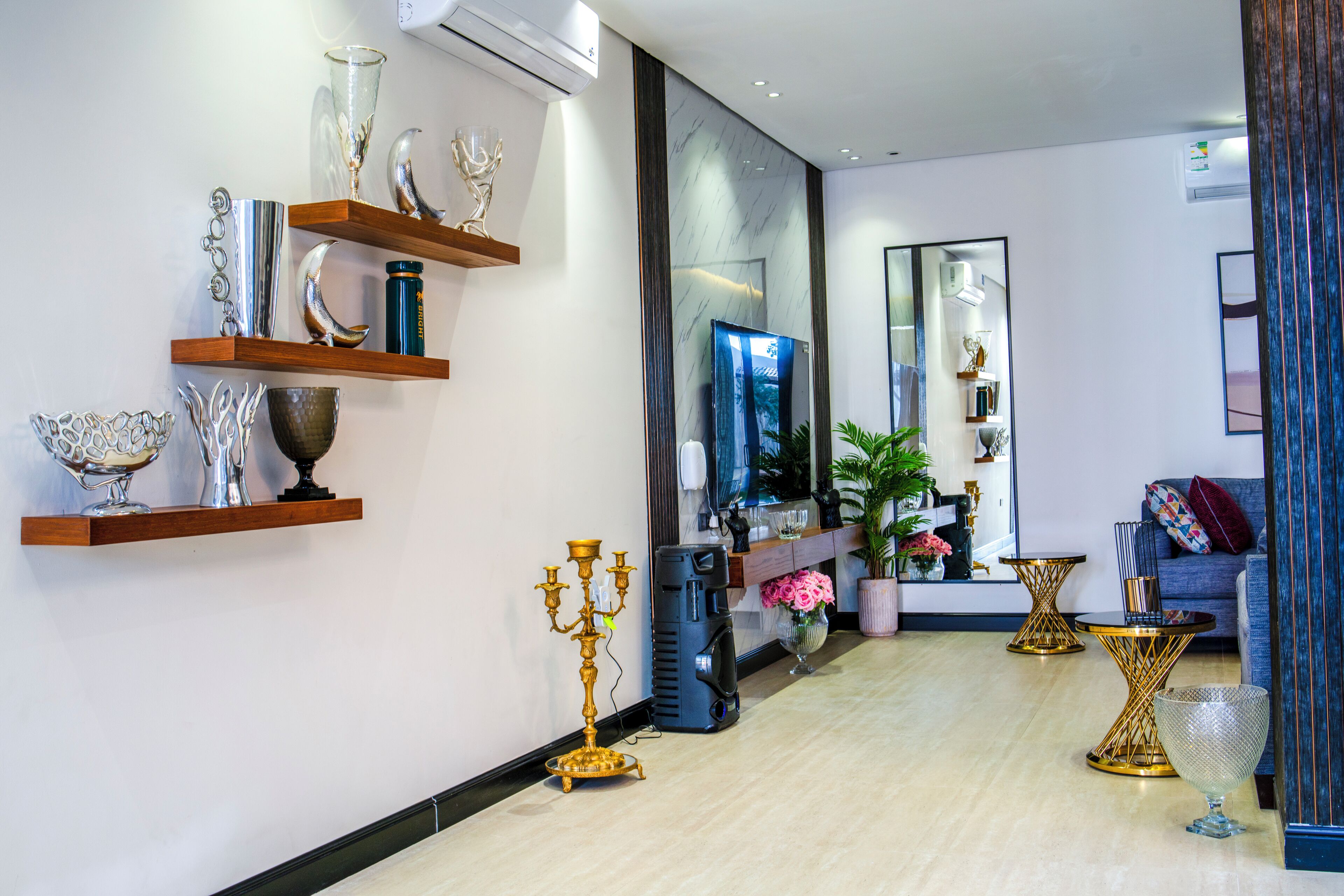 A modern living room with a TV, decorative items on shelves, a sofa, and a coffee table.