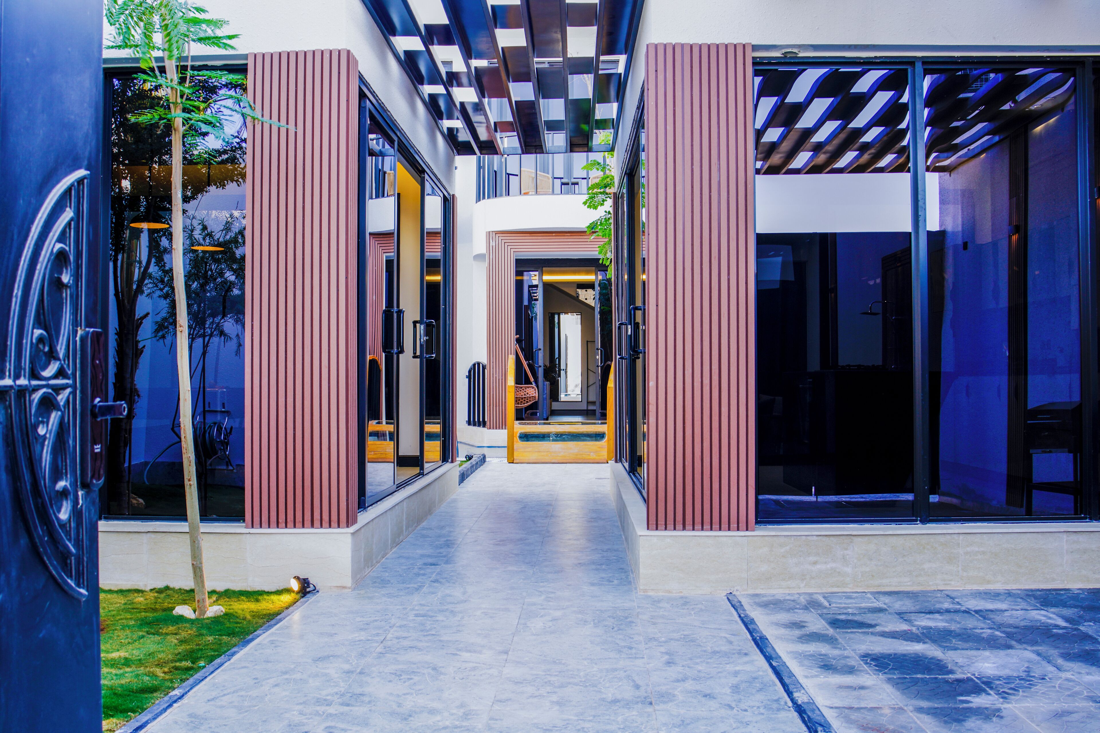 Un edificio moderno con un corredor central, puertas de cristal grandes y una combinación de paredes rojas y blancas.