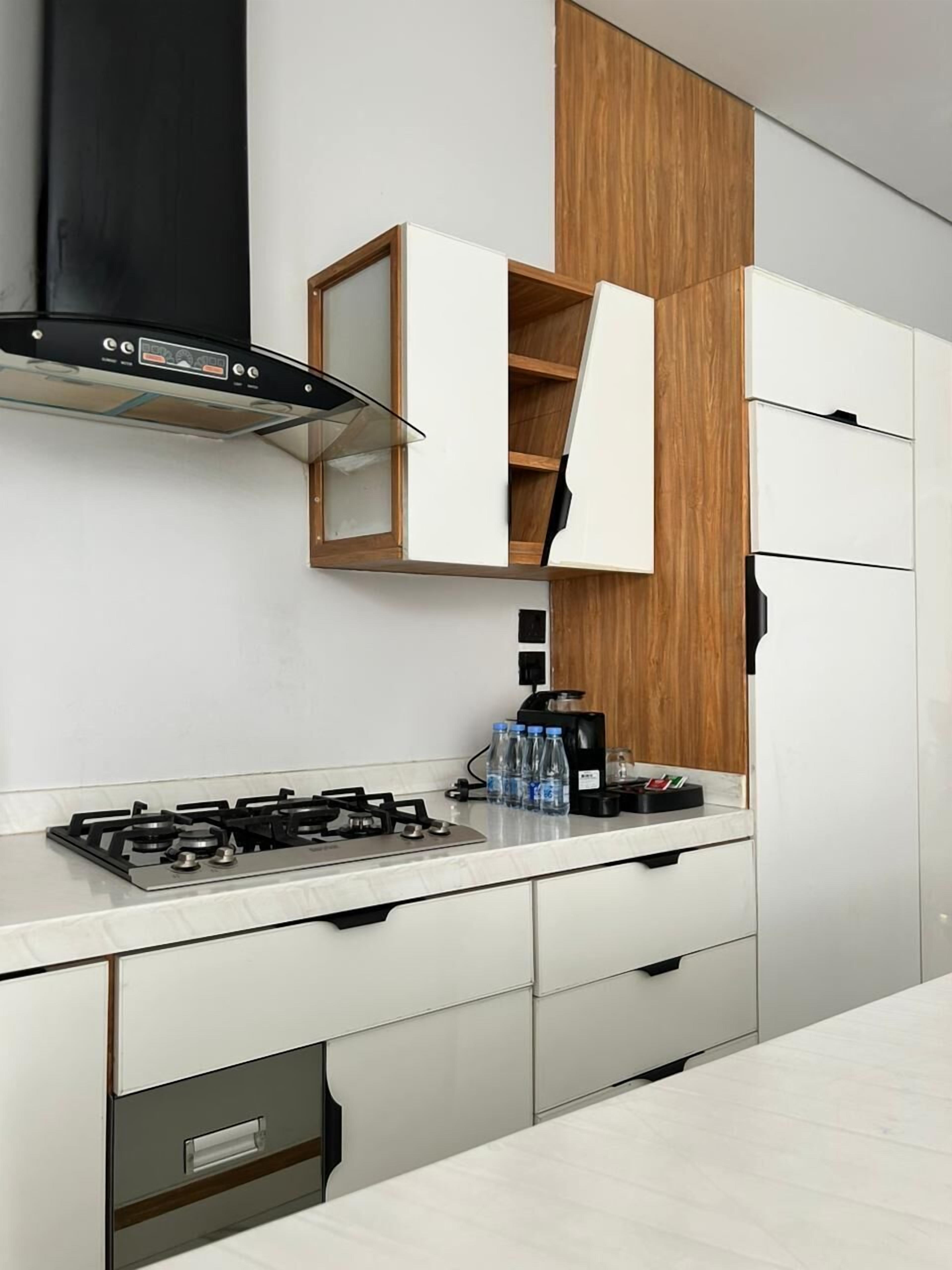 A modern kitchen with a gas stove, white cabinets, a wooden accent wall, and a built-in range hood.