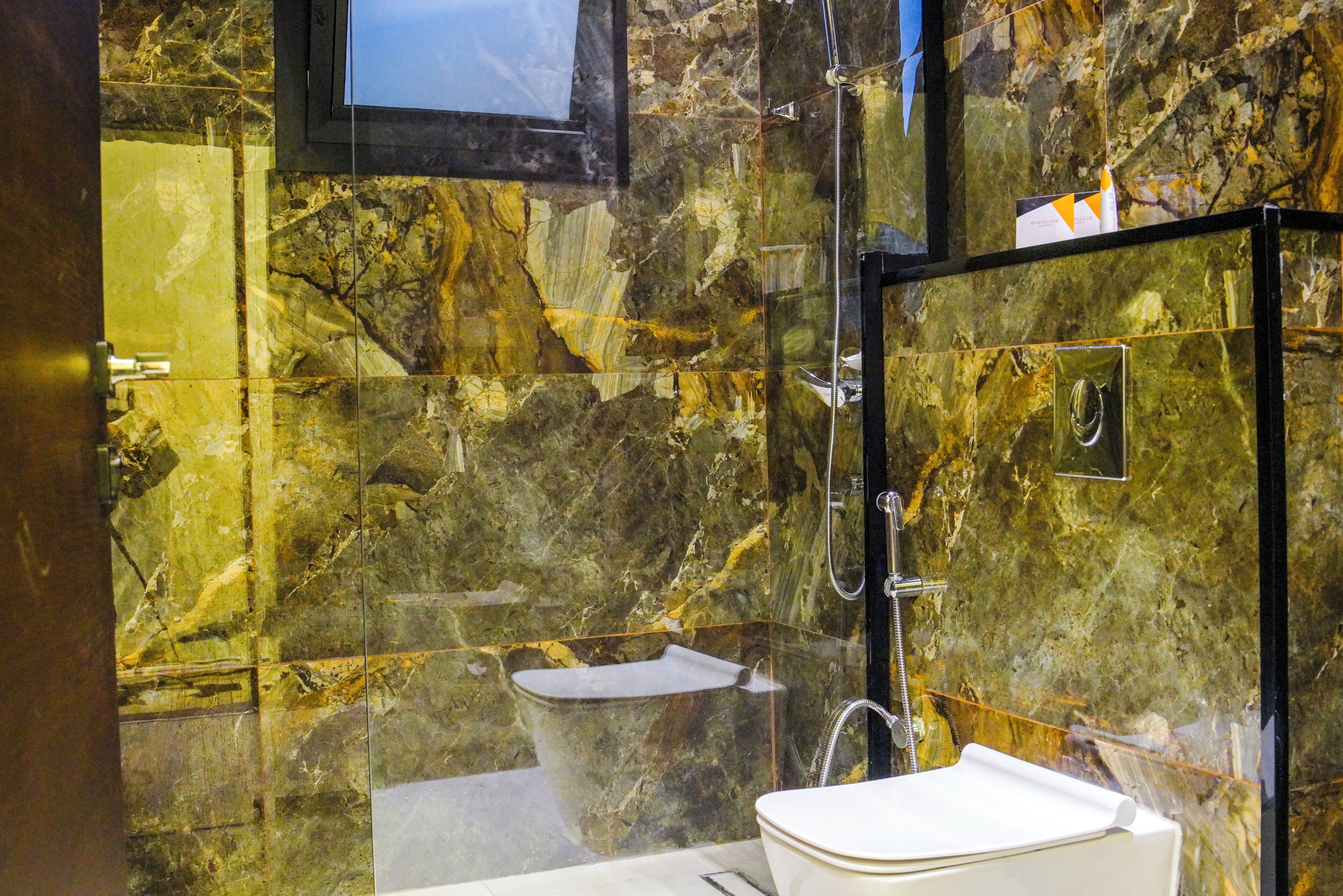 A bathroom with a marble wall, a bathtub, a shower, and a toilet.