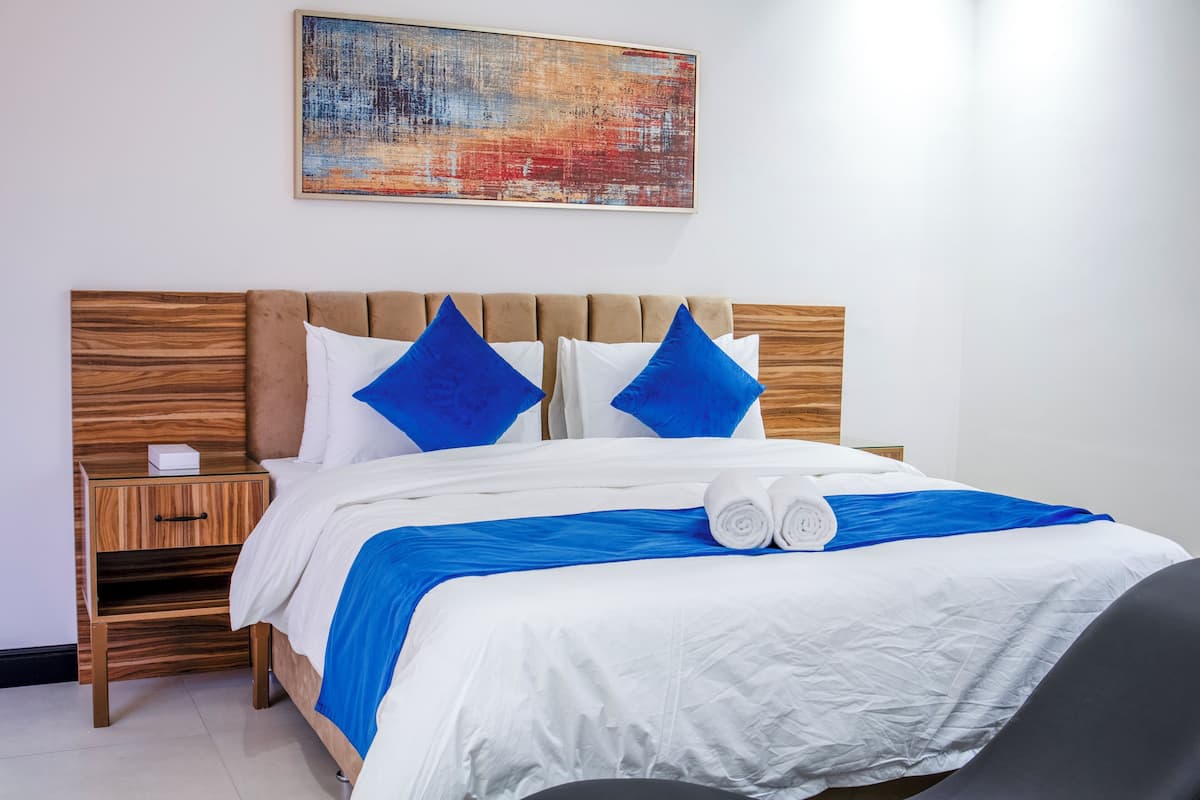 A neatly made bed with blue and white bedding, a wooden headboard, and a small bedside table with a box.