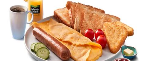 A plate with toast, a sausage, tomatoes, and a glass of orange juice.