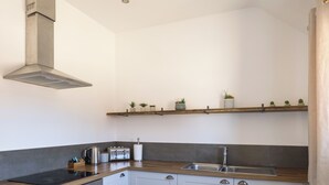 A modern kitchen with a built-in oven, a stovetop, a sink, and a wooden countertop.
