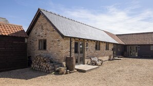 A rustic building with a sloped roof, a wooden bench, and a gravel ground.