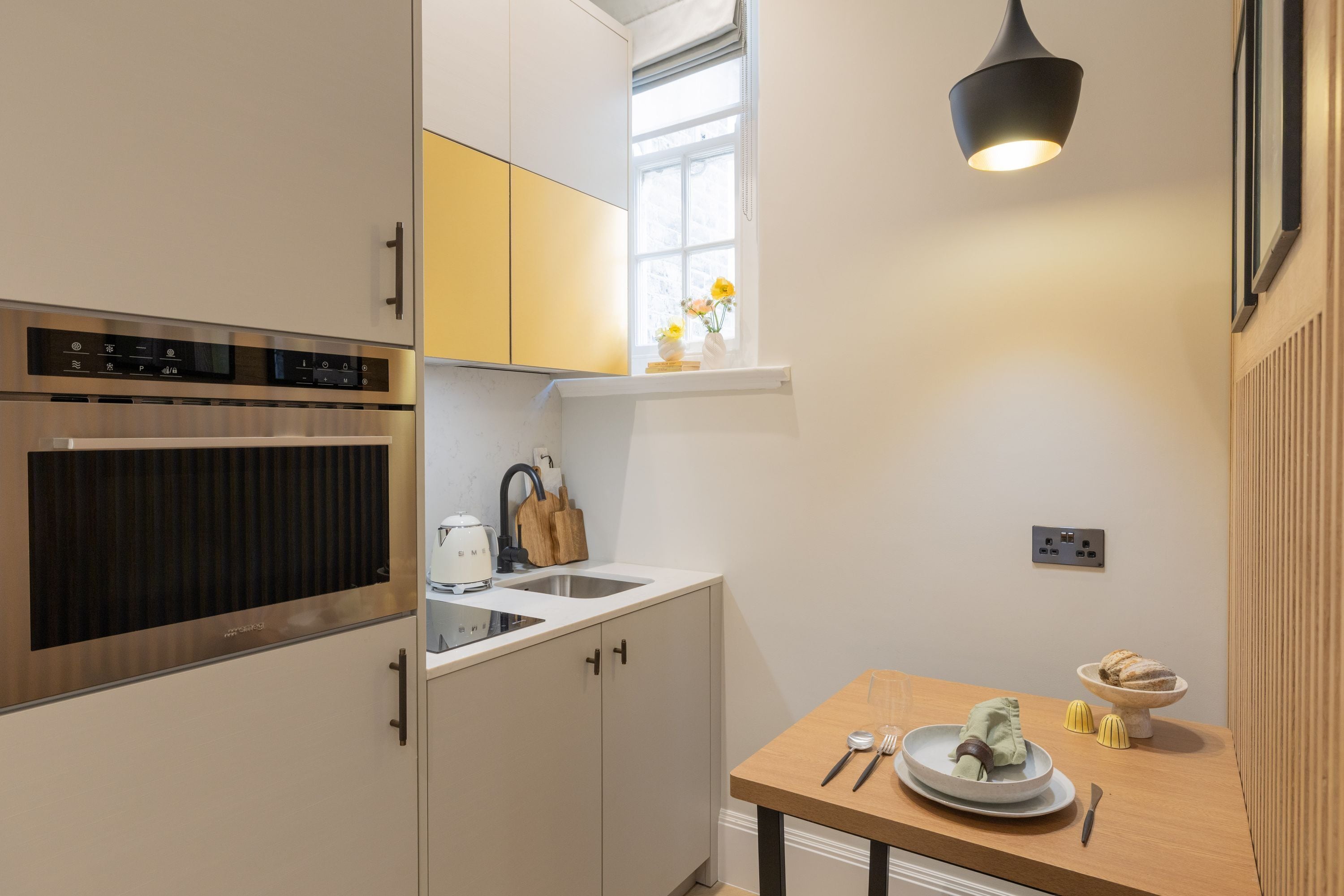 Eine moderne Küche mit integriertem Backofen, einer Spüle und einem Holzespeisetisch mit einem Teller Essen und Besteck.