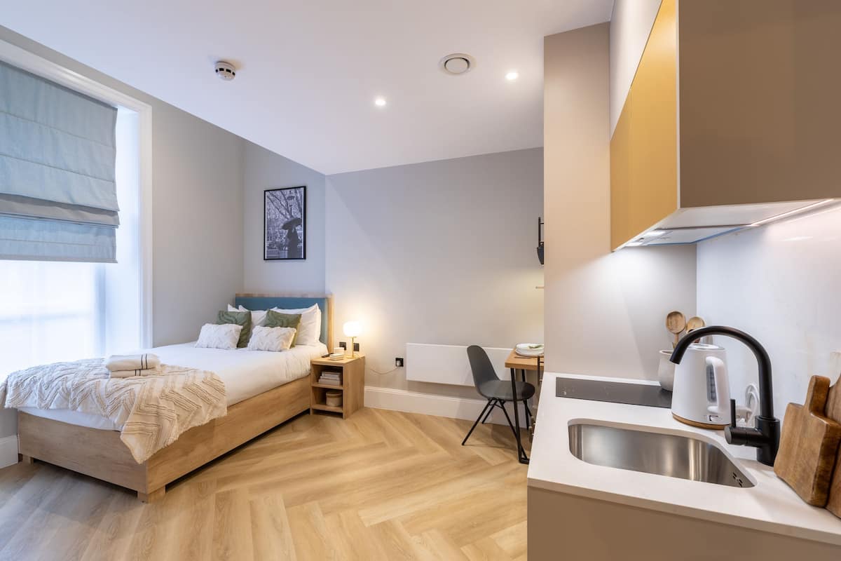 Une chambre moderne avec un lit en bois, une table de chevet et un petit bureau avec une chaise.
