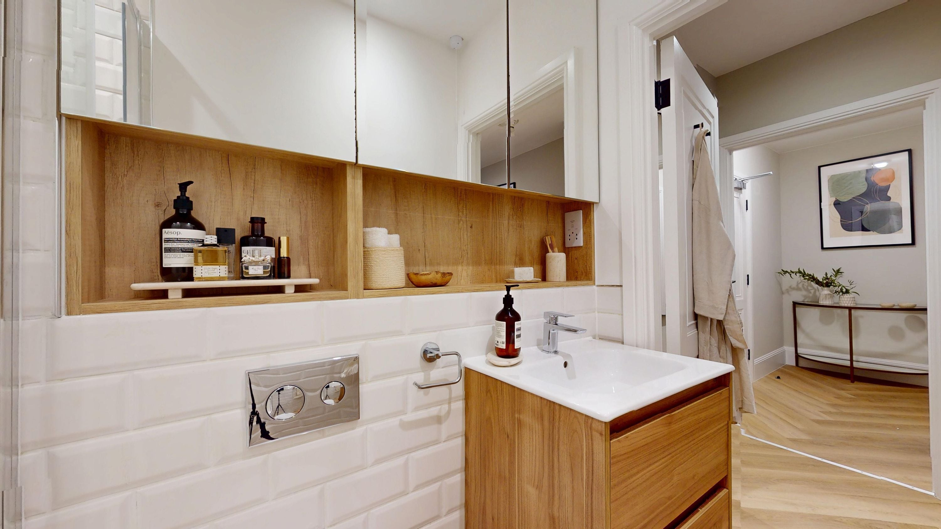 Un baño moderno con tocador de madera, un espejo grande y un lavabo blanco.