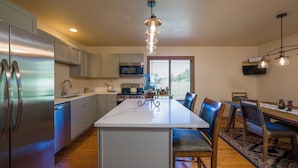 Una cocina moderna con electrodomésticos de acero inoxidable, una isla central y un comedor con sillas y una mesa.