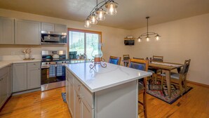 Una cocina moderna con electrodomésticos de acero inoxidable, una isla central y un comedor con mesa y sillas de madera.