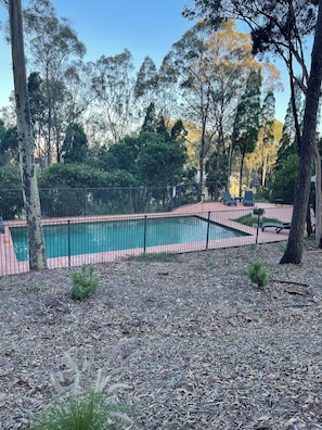 Una piscina al aire libre, sillones reclinables de piscina